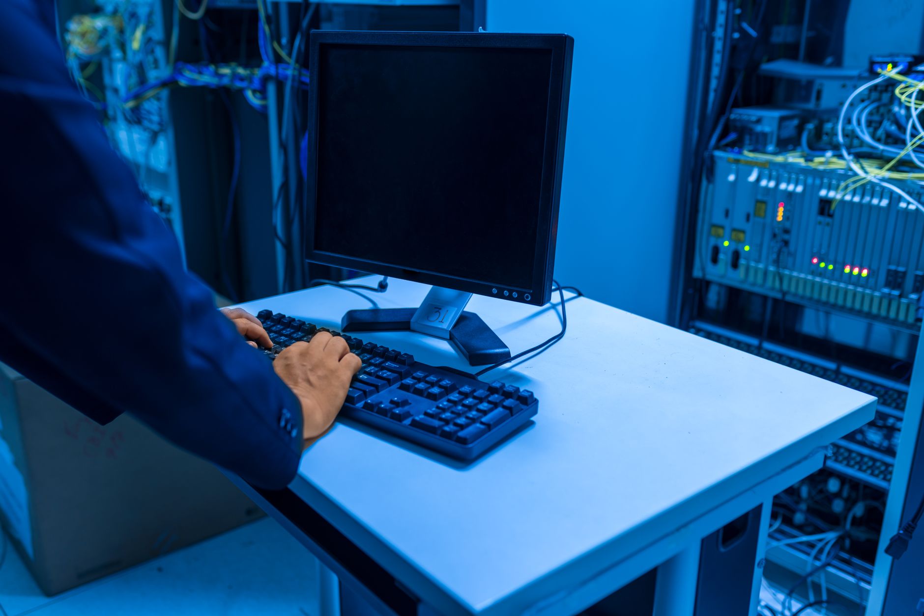 A technician working in a network equipment room with structured cabling and switching gear